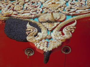 A colony of the giant Asian honey bee (Apis dorsata) engulfing a naga-head motif on the awning of a temple in Chiang Rai province, northern Thailand.