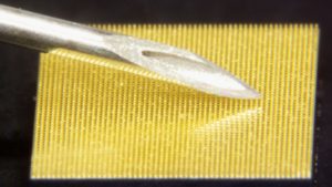 Prototype Nanopatch compared to a needle